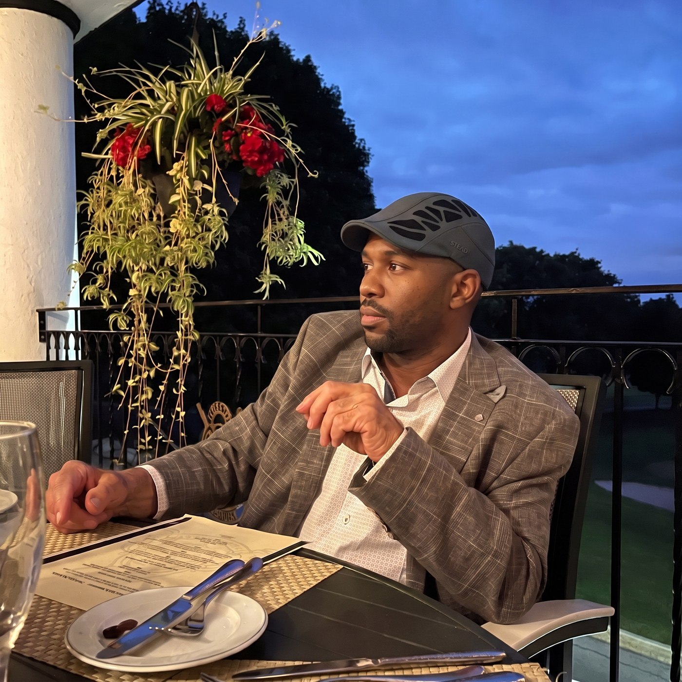 A man in the Aeromesh Evo Cap at a terrace dinner at dusk, blazer and open shirt