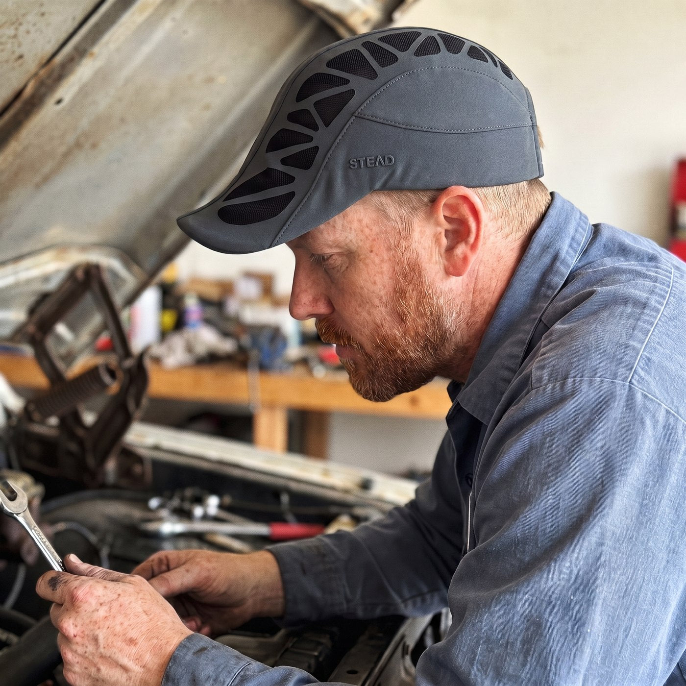 A man in the Aeromesh Evo Cap leaning into the engine bay of his pickup, wrench in hand